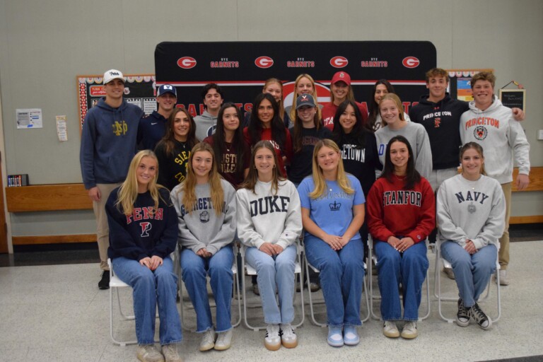 (PHOTO: 22 students at Rye High School signed on to play collegiate sports on Thursday, November 14, 2024. It is the first of an expected three signing ceremonies this year. Front row, left to right: Mary Sack, Ella Erickson, Caroline Doyle, Katherine Ebeling, Mia Padovano, Haley Kloepfer  Second row, left to right: Kayla Lombardo, Ella Ryan, Tara Laschever, Clementine Riegelhaupt, Juliete Rotondo, Elena Chesley,  Back row: Chris Iuliano, Tucker Hess, Ty Ramachandran, Alexandra Ausfahl, Megan Tiedemann, Fiona Asgeirsson, Kathleen Denvir, Matthew Giannetti,Tyler McDermott. Not pictured: Margaret (Maggie) Gallagher.)