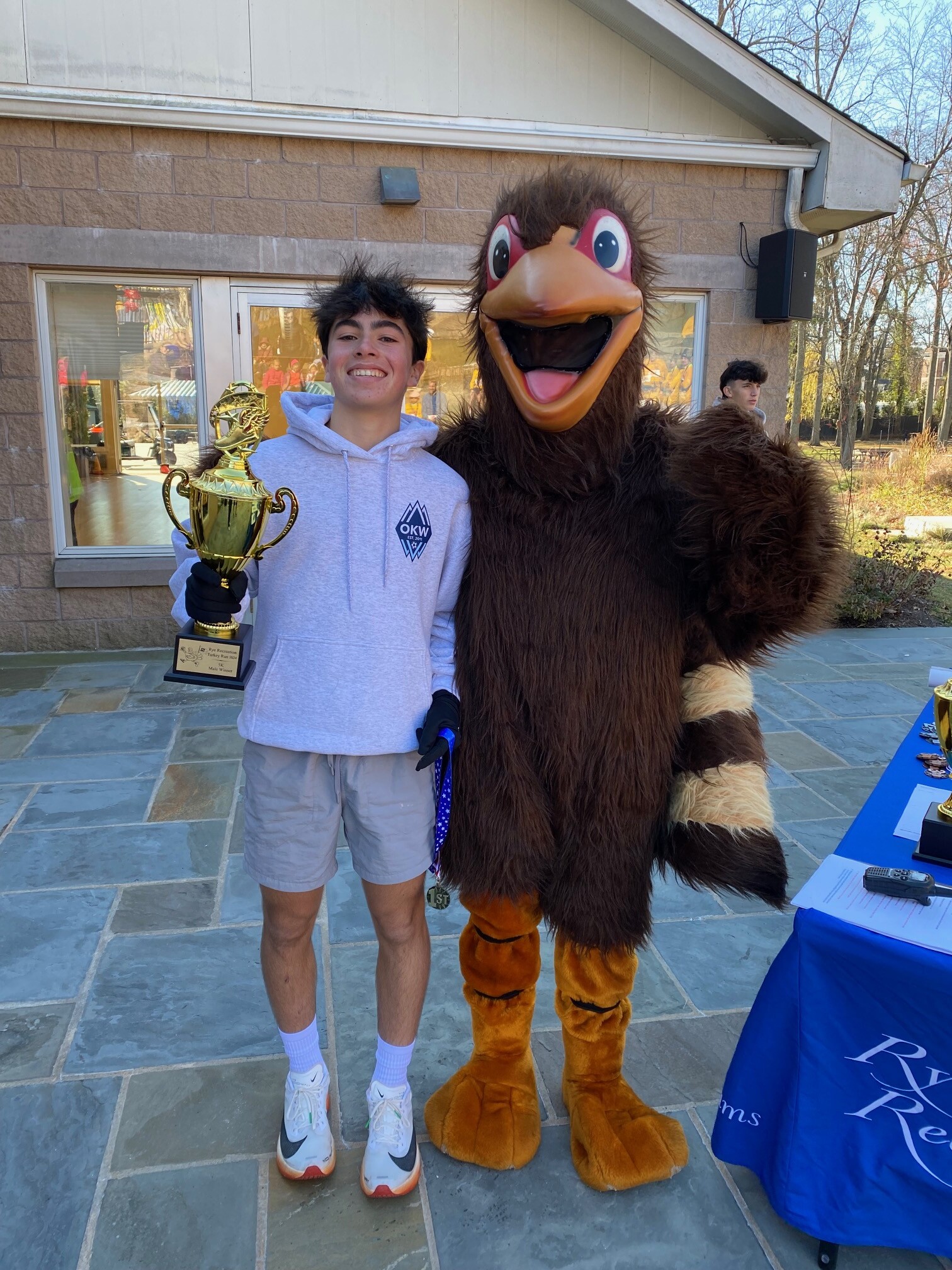 (PHOTO: The Rye Rec turkey posing with the 5K overall winner, Owen Wagner.)