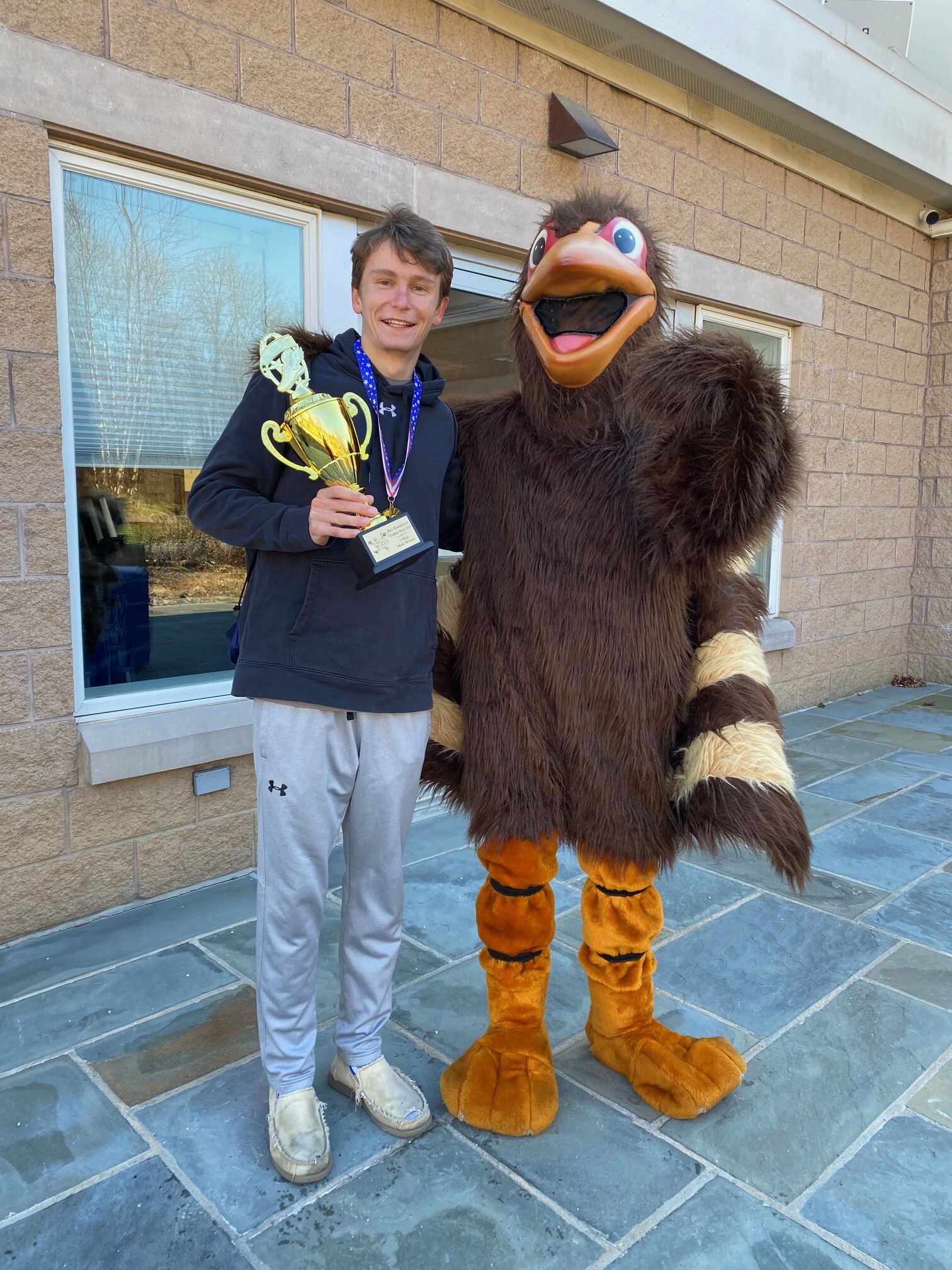 (PHOTO: 5-mile winner Ian Tibbals also posed with the turkey and his trophy.)