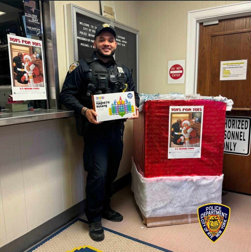 (PHOTO: Rye PD Officer Victor Rodriguez protects the donations for the Rye PBA's annual Toys for Tots drive at Rye Police headquarters. Contributed.)