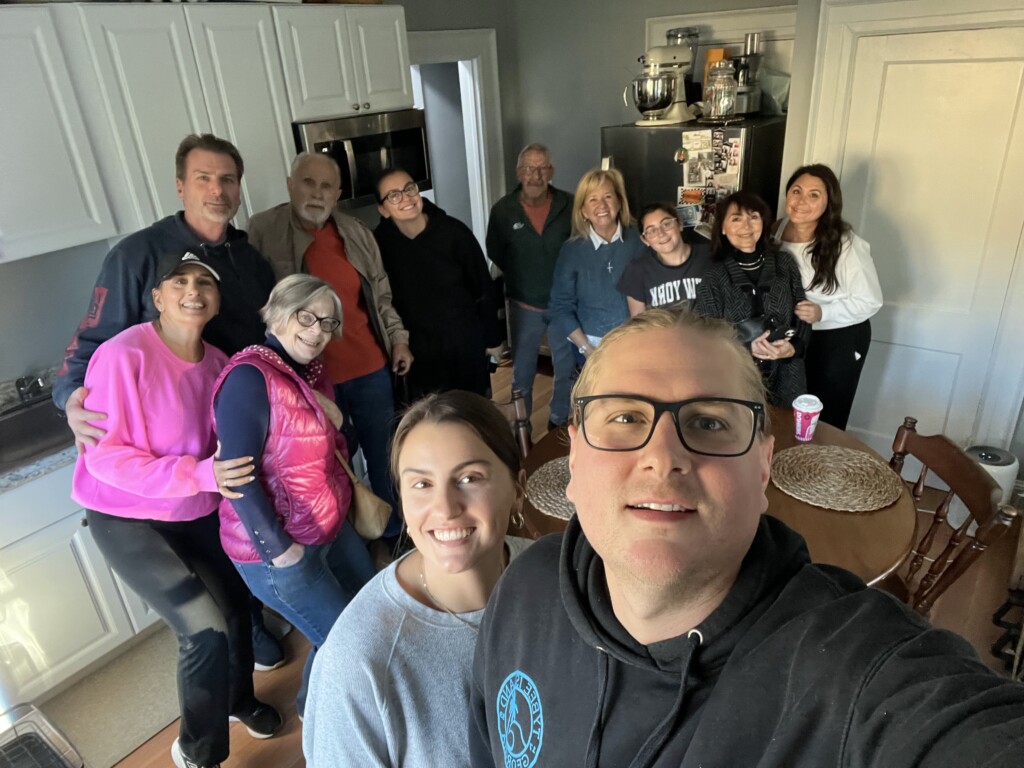 (PHOTO: The extended family recently came to inspect the family home at 219 Central Avenue: (left to right): Joanie Buckley, Patti Mitten, Tom Mitten (Kelly’s dad), John Grippo, Kristina Mitten (Kelly’s sister), Arthur Fisher (Joanie’s partner), Lori Grippo (Aunt who also lived in the house), Mikaela Ferraro (cousin), Lisa Griffin (Kelly’s grandma who also lived in the house), Stephanie Ferraro (aunt). New family owners Kelly Mitten and Toby Waring are in the foreground. Contributed.) 