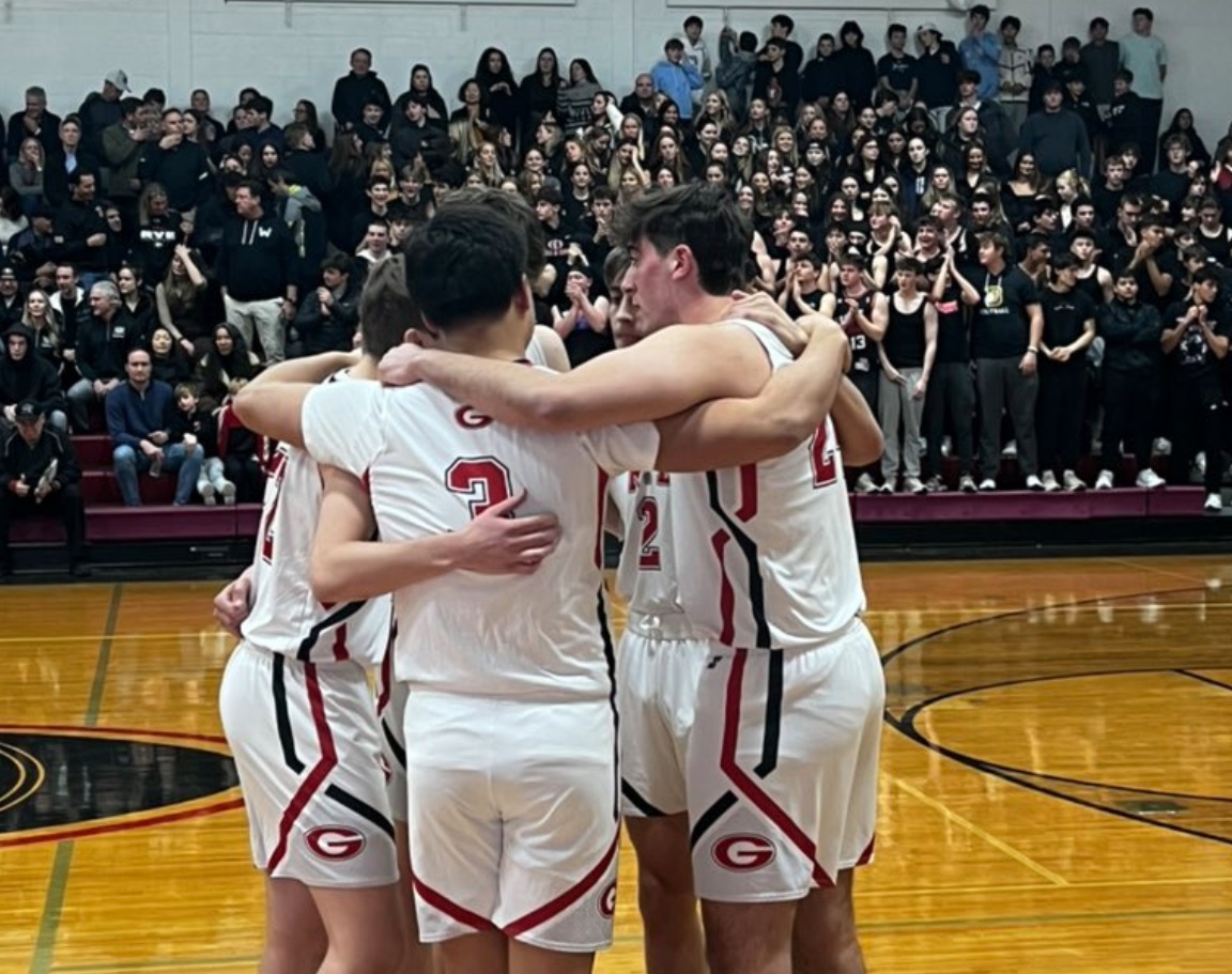 (PHOTO: Rye Boys Basketball huddling in front of a packed crowd in the Rye High School Gym on Friday, January 10. Credit: Rye Athletics)