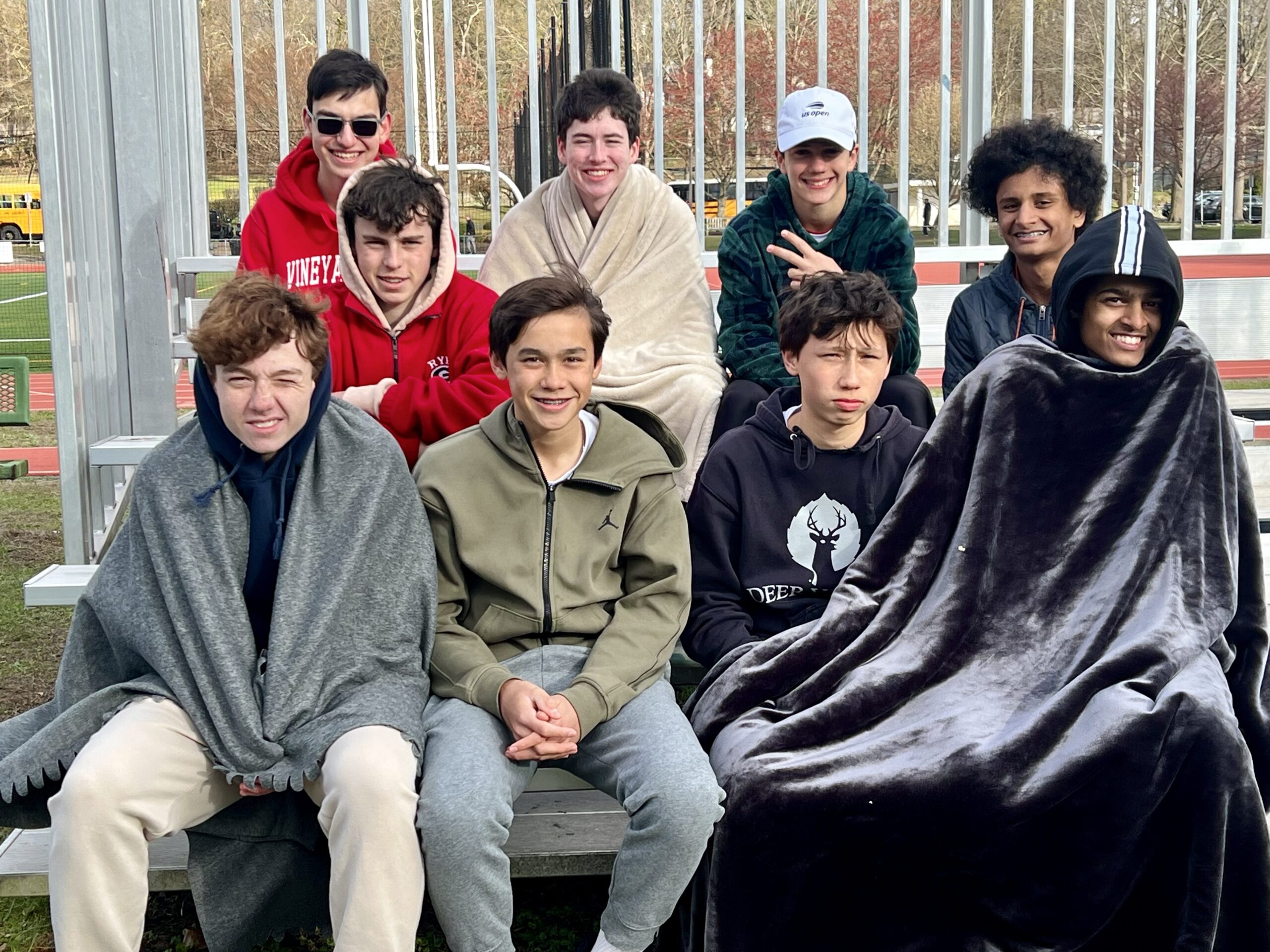 (PHOTO: Members of the Rye Boys Tennis Team support their teammates from the sidelines on a chilly April 8, 2025. Contributed.)