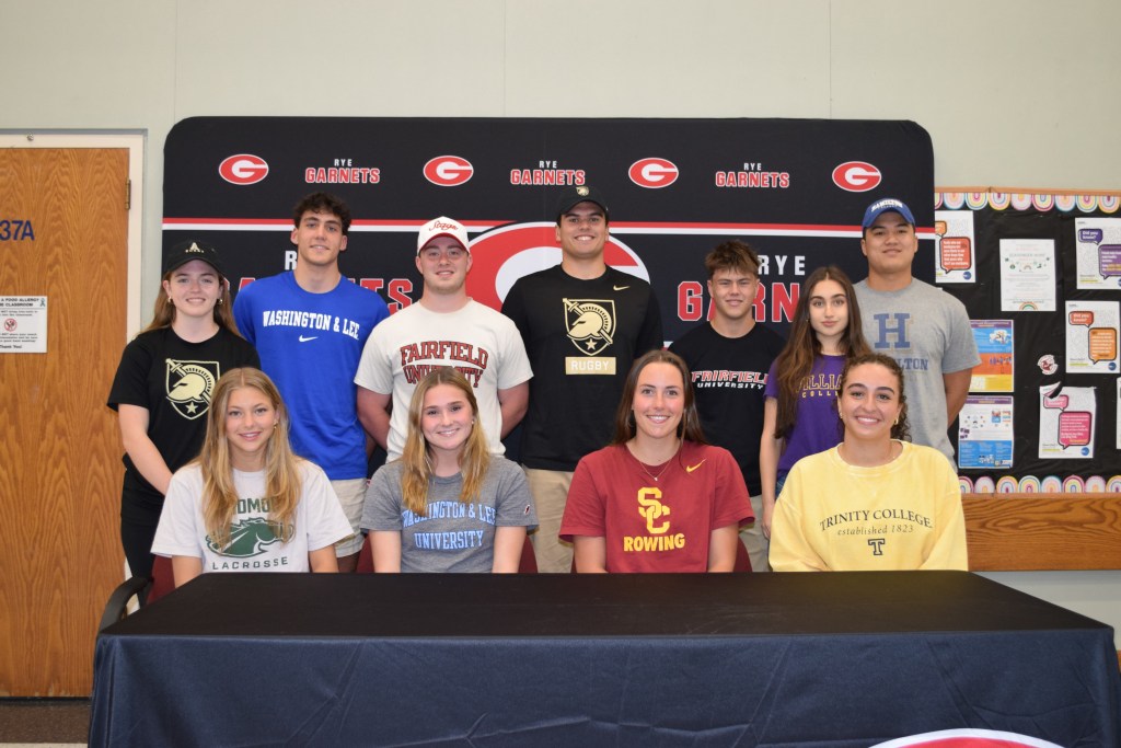 (PHOTO: Eleven Eleven Rye High School seniors committed to play NCAA college sports on Tuesday, May 20, 2025: Bottom row, L to R: Lucy Wyckoff, Taylor Bainbridge, Meg Owens, Charlize Tavitian. Back row, L to R: Molly Kennedy, Kaden Zion, Owen Saya, Patrick McGuire, Archer Fenton, Kate Morreale, Andrew Wilmarth. Not pictured: Bill Chen, Anna Nolasco. Contributed.)