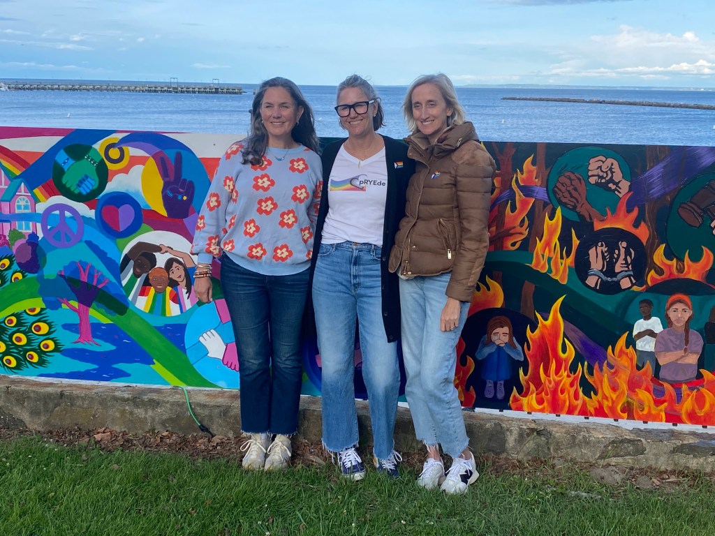 (PHOTO: The Fifth Annual Pride Month Celebration was held in Rye Town Park on May 31, 2025, organized by the Town of Rye, Rye Town Park, and pRYEde. pRYEde founders Alison Cupp Relyea, Amanda Timchak and Genevieve Weber in front of the new pride mural.)