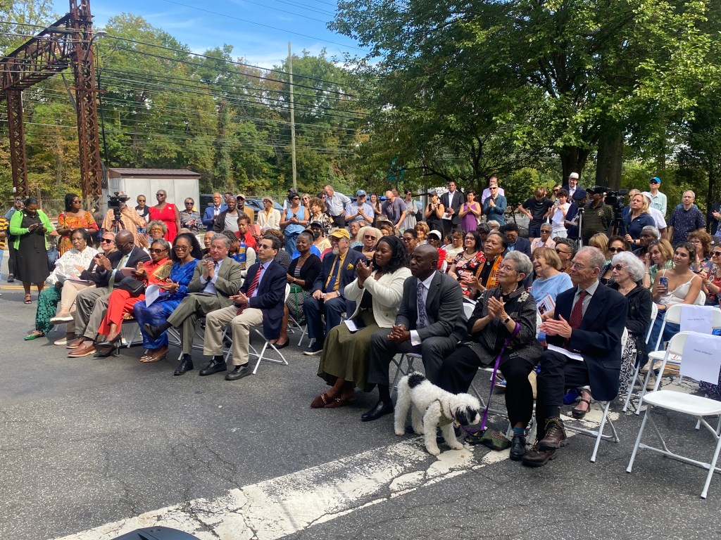 (PHOTO: The Paul & Orial Redd Way street naming at the Rye train station on September 27, 2025. VIPs in the front row and the assembled crowd.)