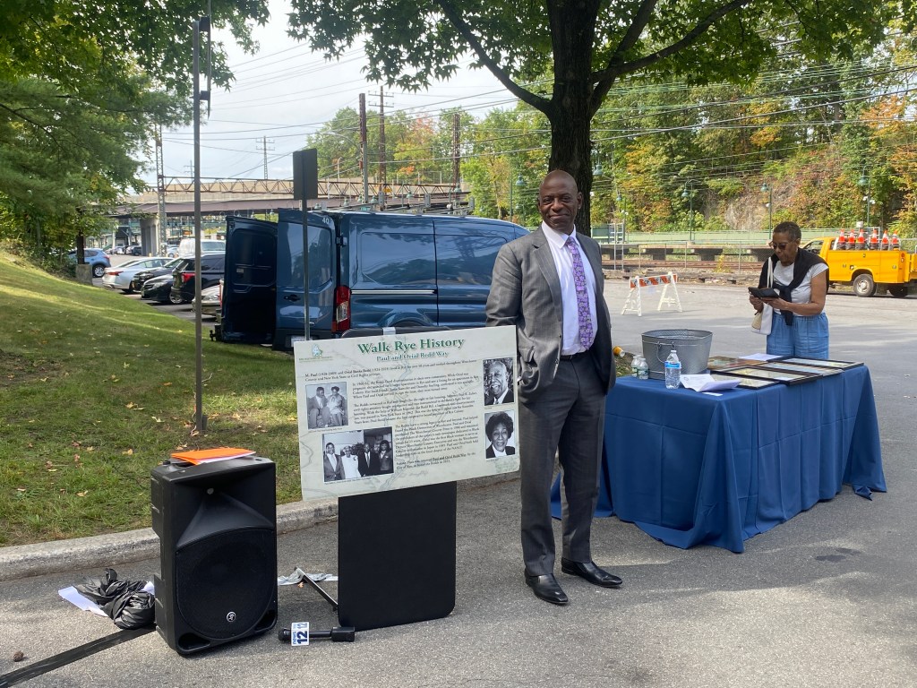 (PHOTO: The Paul & Orial Redd Way street naming at the Rye train station on September 27, 2025. Paul Redd Jr. alongside a new Rye Historical Society interpretive sign about the Redds that will be installed in the train station plaza.)