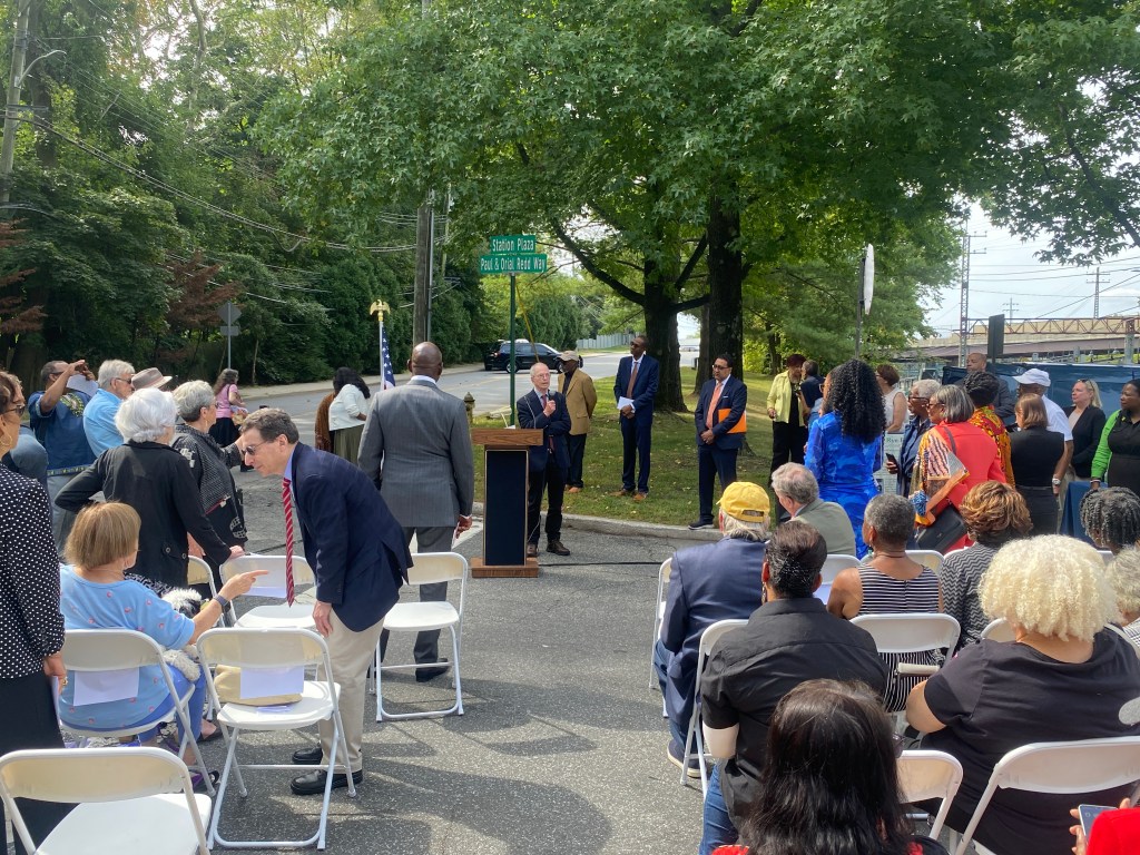 (PHOTO: The Paul & Orial Redd Way street naming at the Rye train station on September 27, 2025. Peter Sterling, son of Dorothy Sterling, speaking to the crowd. When he and his sister Anne were children, a cross was set on fire in their yard on Kirby Lane North.)