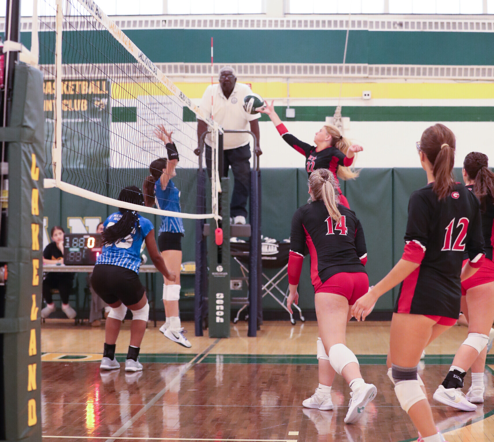 (PHOTO: Rye Volleyball's Olivia Lewis (#22) tapping the ball over the net on Saturday, September 20. Also pictured: Sofia Jovanovic (#12) and Katelyn Haines (#14). Credit: Ethan Lewis.)