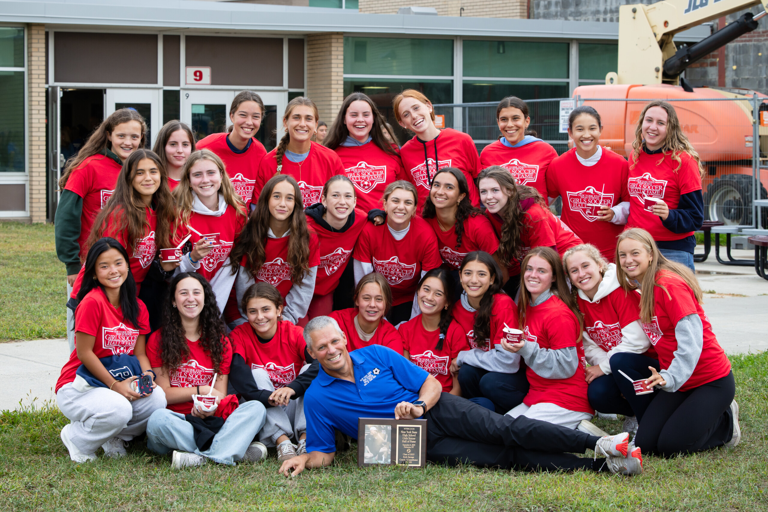 (PHOTO: The 2025 Rye Girls Soccer Team surrounding Head Coach Rich Savage after his induction into the NYS Girls Soccer Hall of Fame on Saturday, September 6. Contributed.)