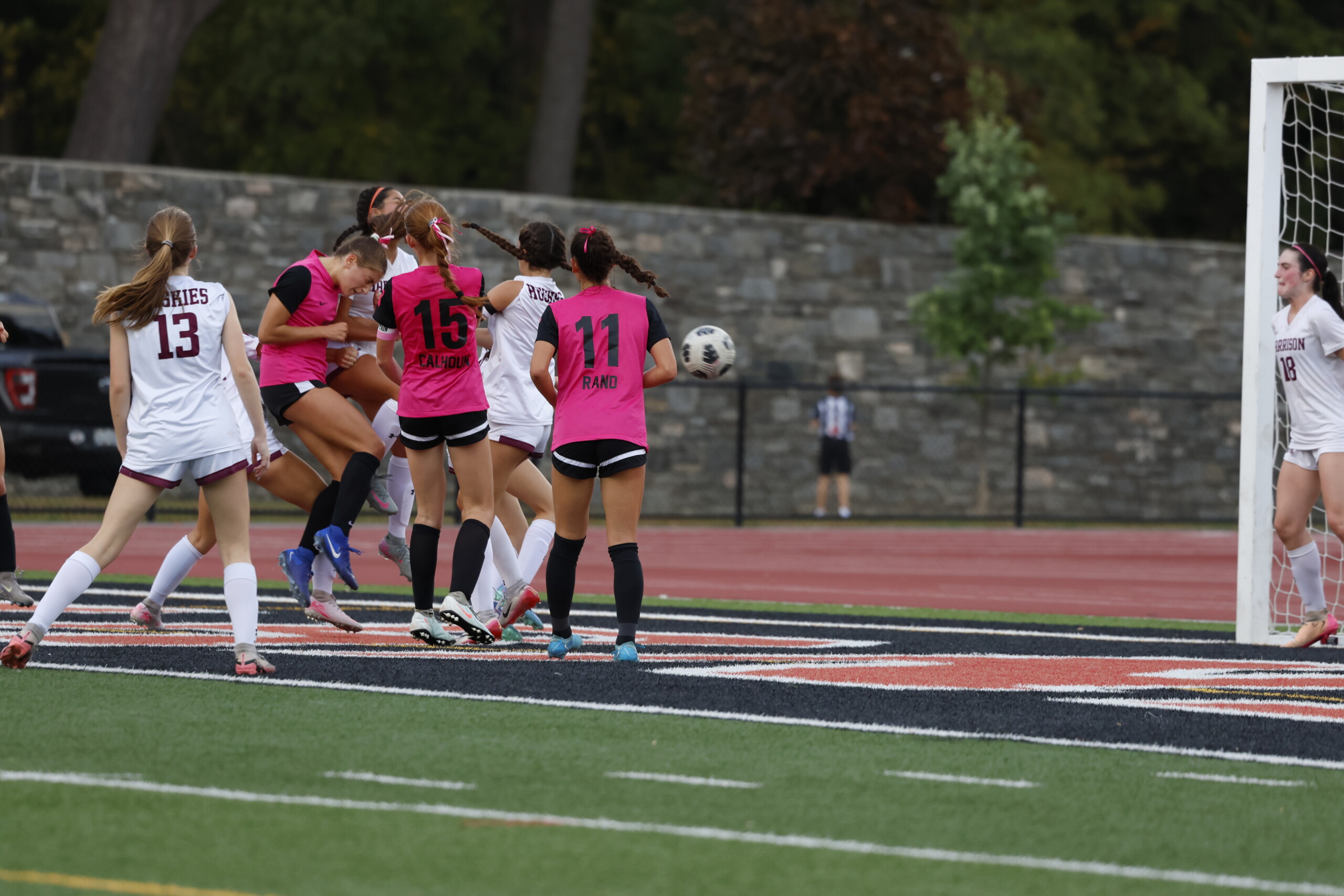 (PHOTO: Hannah Jachman scores a header goal on October 7, 2025, with teammates Parker Calhoun (#15) and Shira Rand (#11) also in the area. Credit: Alvar Lee.)