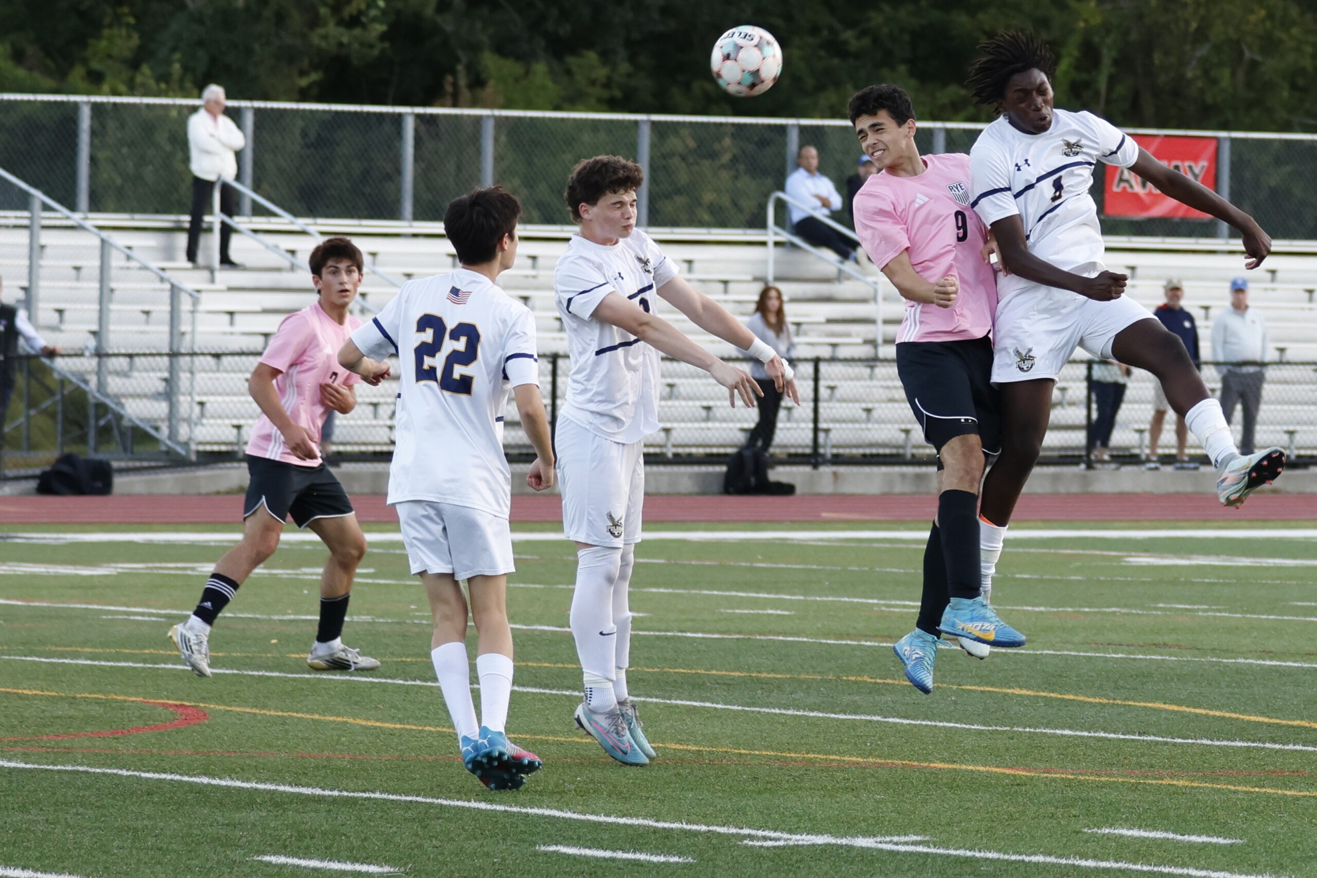 (PHOTO: Rye Boys Soccer's Eddie Kehoe (#9 pink) goes up for a header against Pelham on October 8, 2025. Credit: Alvar Lee.)