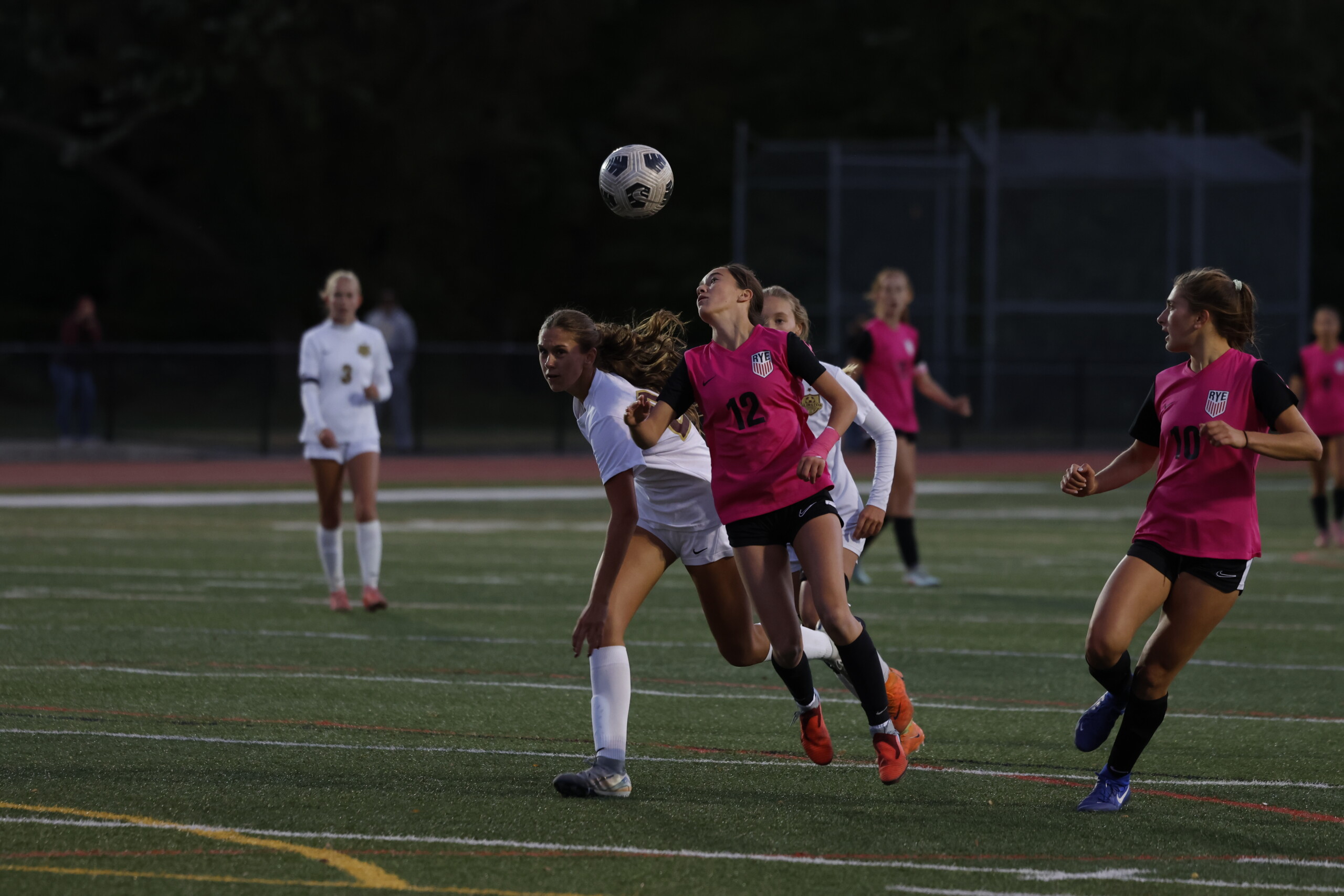 (PHOTO: Rye Girls Soccer' Harkin Brown (#12) contests a header against Arlington on October 16, 2025. Also pictured: #10 Hannah Jachman. Credit: Alvar Lee.)
