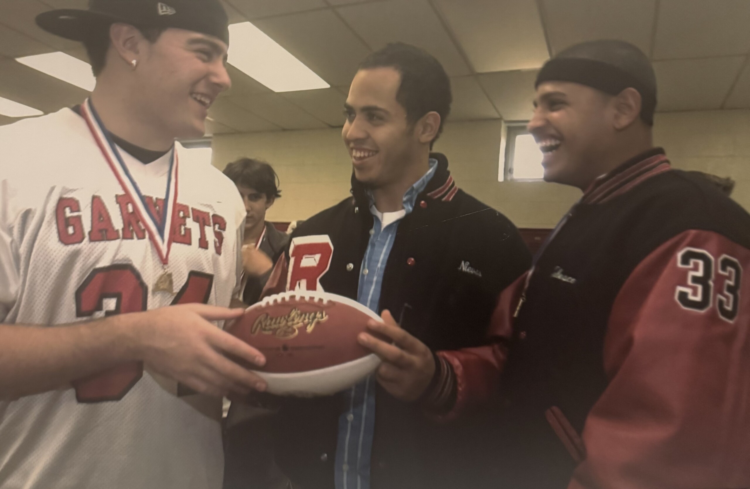 (PHOTO: The State championship ball that Rye earned in 2005, which all players signed. Pictured L to R: Peter Longo, Bam Bam, David Telesco. Telesco ran for 110 yards in the 28-7 victory. Contributed.)