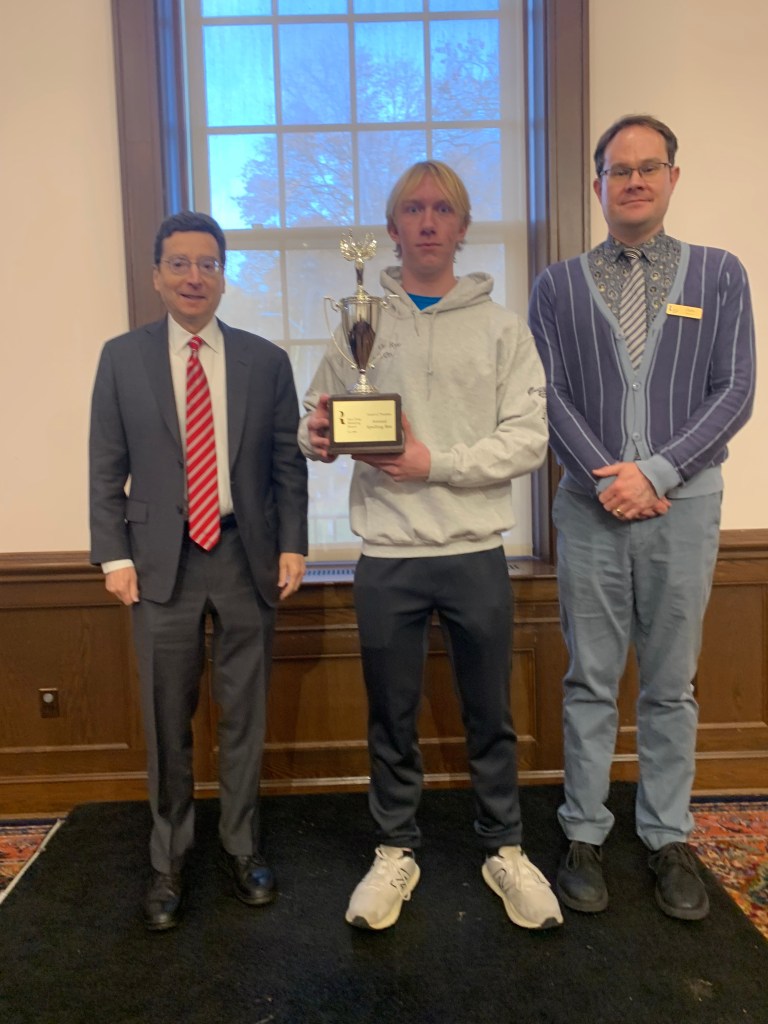(PHOTO: High school senior and winner Calvin Holler at the Eighth Annual Rye Free Reading Room Spelling Bee with Rye Mayor Josh Cohn and Rye Free Reading Room Library Director Chris Shoemaker on November 11, 2025. Contributed.)