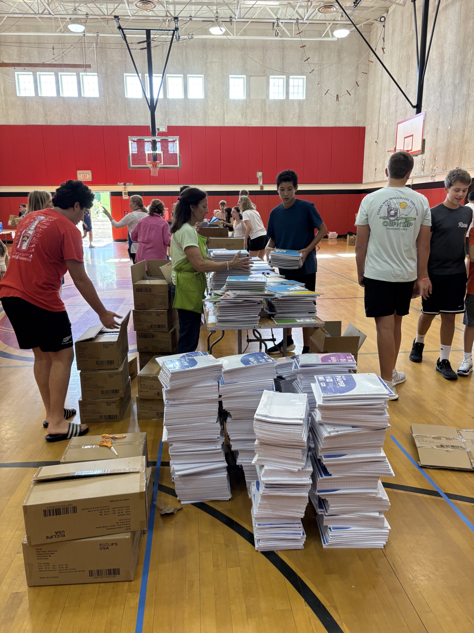 (PHOTO: Volunteers organizing school supplies for Mission Backpack in the Rye High School gym. Contributed.)