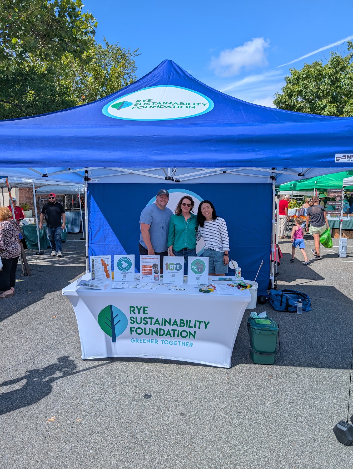 (PHOTO: Rye Sustainability Foundation promotional booth being run by Hilary Garland, Sawako Ward and Rob Motto at the Rye Farmers Market. Contributed.)