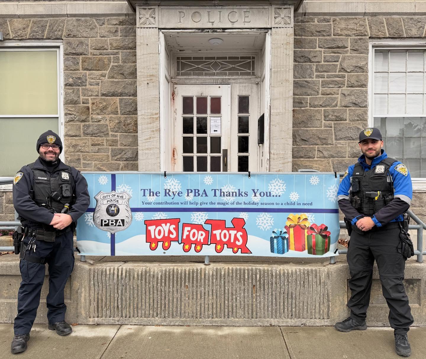 (PHOTO: Rye Police Officers Jesse Calcagni and JP Anjo protect the donations for the Rye PBA's annual Toys for Tots drive at Rye Police headquarters. Contributed.)