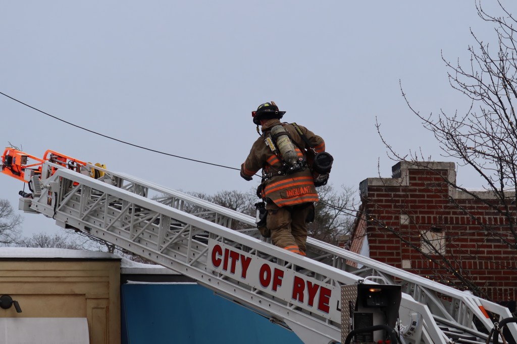 (PHOTO: Rye FD Firefighter Sal Inguanti, climbs the aerial ladder to access the roof of Aurora Restaurant in downtown Rye at 60 Purchase Street on Wednesday afternoon, January 28, 2026. Source: Rye FD.)