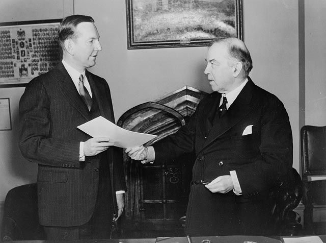 (PHOTO: Jay Pierrepont Moffat (left), United States Ambassador to Canada, and Rt. Hon. W.L. Mackenzie King (right) at the exchange of notes between the governments of Canada and the United States on the Alaska Highway construction terms. Public Domain via Wikimedia Commons.)