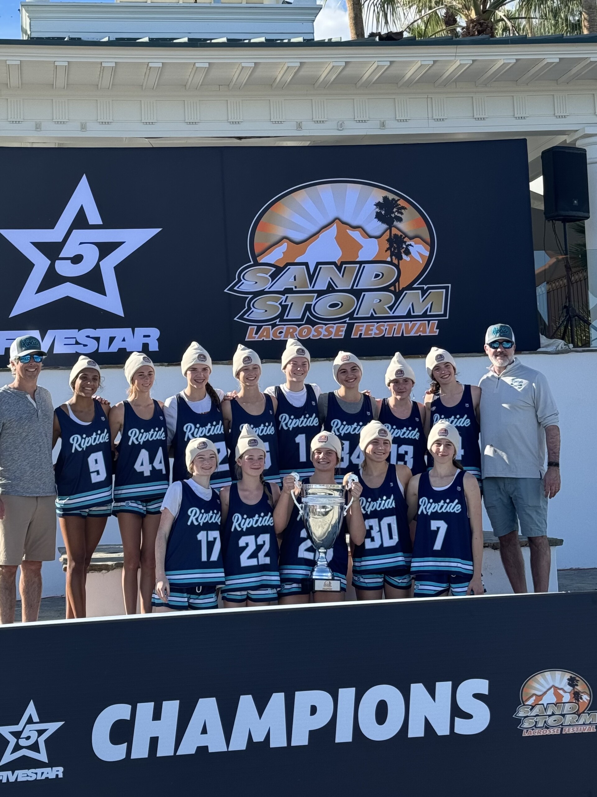 (PHOTO: The Rye Riptide independent lacrosse team captured the top division 2029 AA Girls Championship at the SandStorm Lacrosse Festival in Indio, California on January 17 and 18, 2026. Standing (L to R): Coach Matt Pymm, Avni Patel, Maddie Treacy, Dylan Ehrlich, Reilly Pymm, Arianna Lewis. Daphne Mallios, Cassidy Waters, Riley Driscoll, Coach Justin Driscoll. Kneeling (L to R): Hillary Donahue, Harper Howell, Sally Dance, Caroline Kmetz, Rose Denvir. Not Pictured: Ella McKay & Fleur Kevorkian. Contributed.)