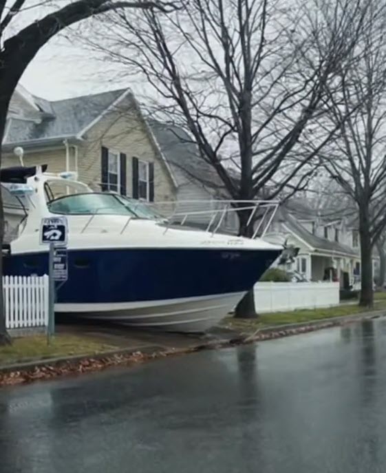 (PHOTO: To combat flooding, the new Rye Aquatic Resilience & Biodiversity Preservation Ordinance (RARBPO) requires every single-family homeowner to purchase and maintain a watercraft of at least 30 feet in length—parked curbside and ready for immediate deployment. Credit: THE RYE ONION Fake News, Really Rye. A Satirical Series Presented by MyRye.com. Image created with AI.)