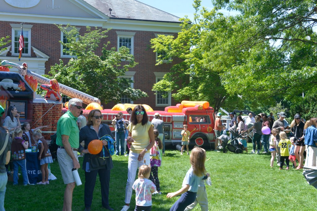 (PHOTO: Families gathered on the Village Green for the Library's Vehicle Fair. Credit: Claire Hovers.)