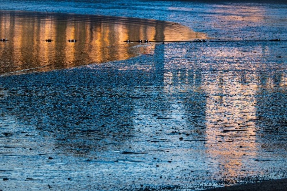 (PHOTO: Reflections of Playland. The Playland Bathing pavilion is mirrored in the rippling tide. By Stacey Massey, author of First Light, Rye.)