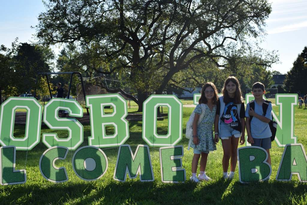 Students with a welcome back sign outside school