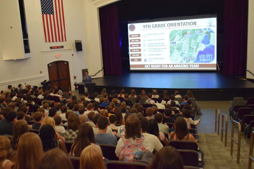 Principal speaking to students in auditorium